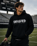 Black Never Satisfied hooded sweatshirt shown at a football field