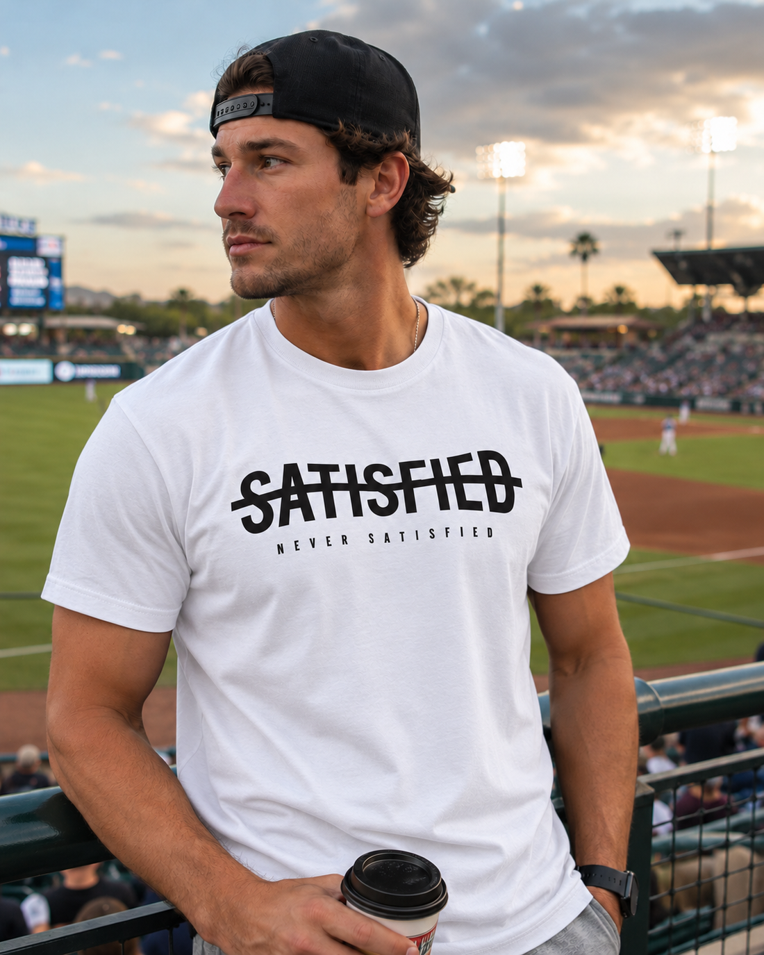 White Never Satisfied T-shirt color mockup at a baseball stadium